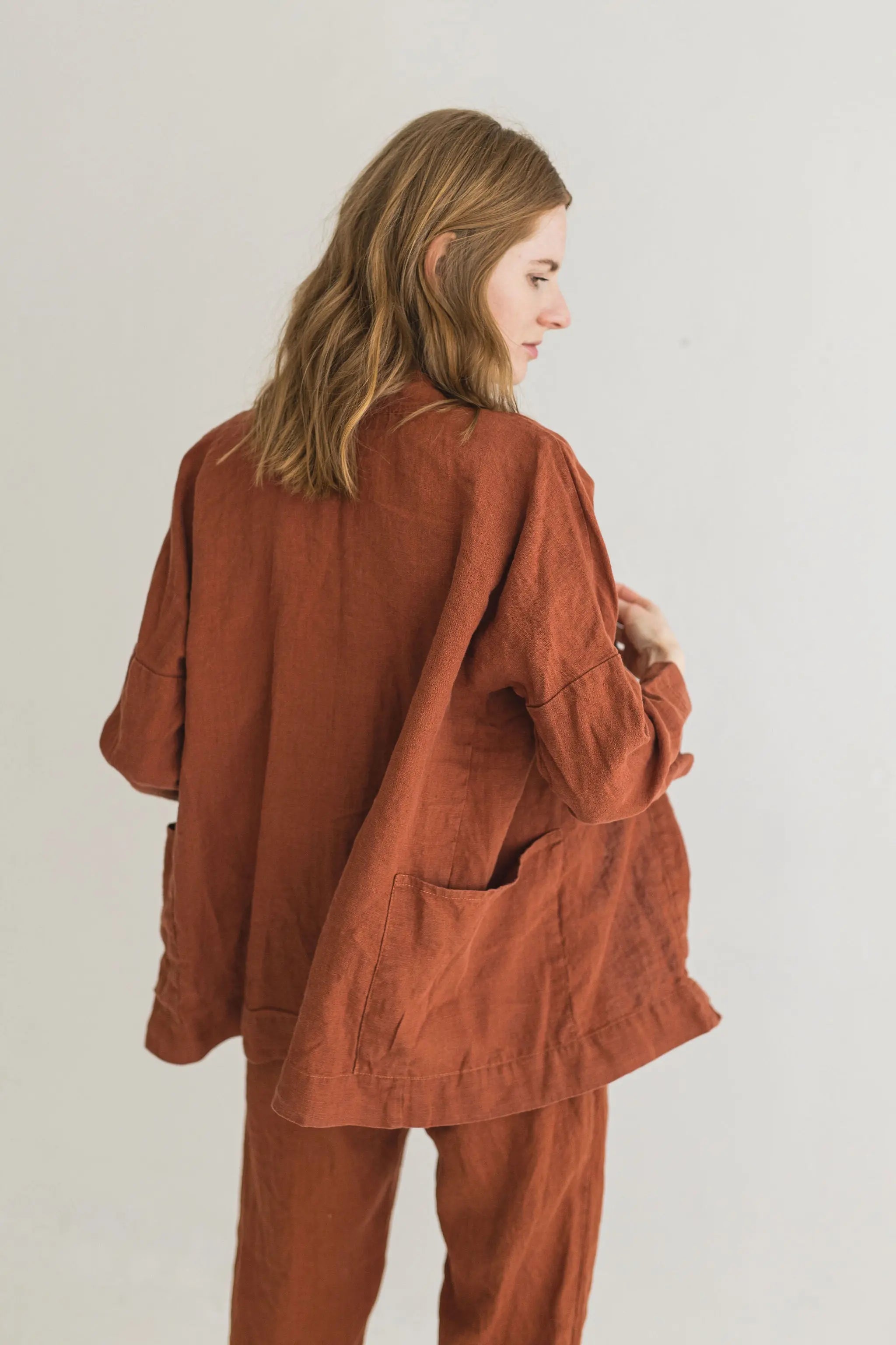 Person wearing a brown jacket and pants on a plain background