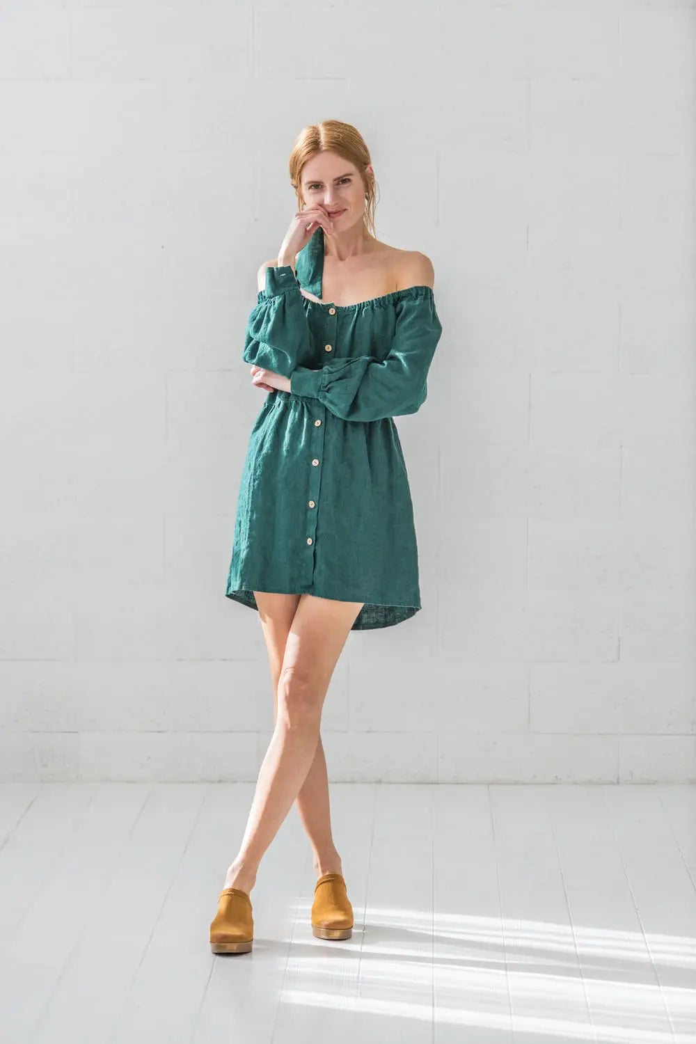 Full length view of linen balloon sleeve mini dress with off-shoulder neckline styled with wooden clogs