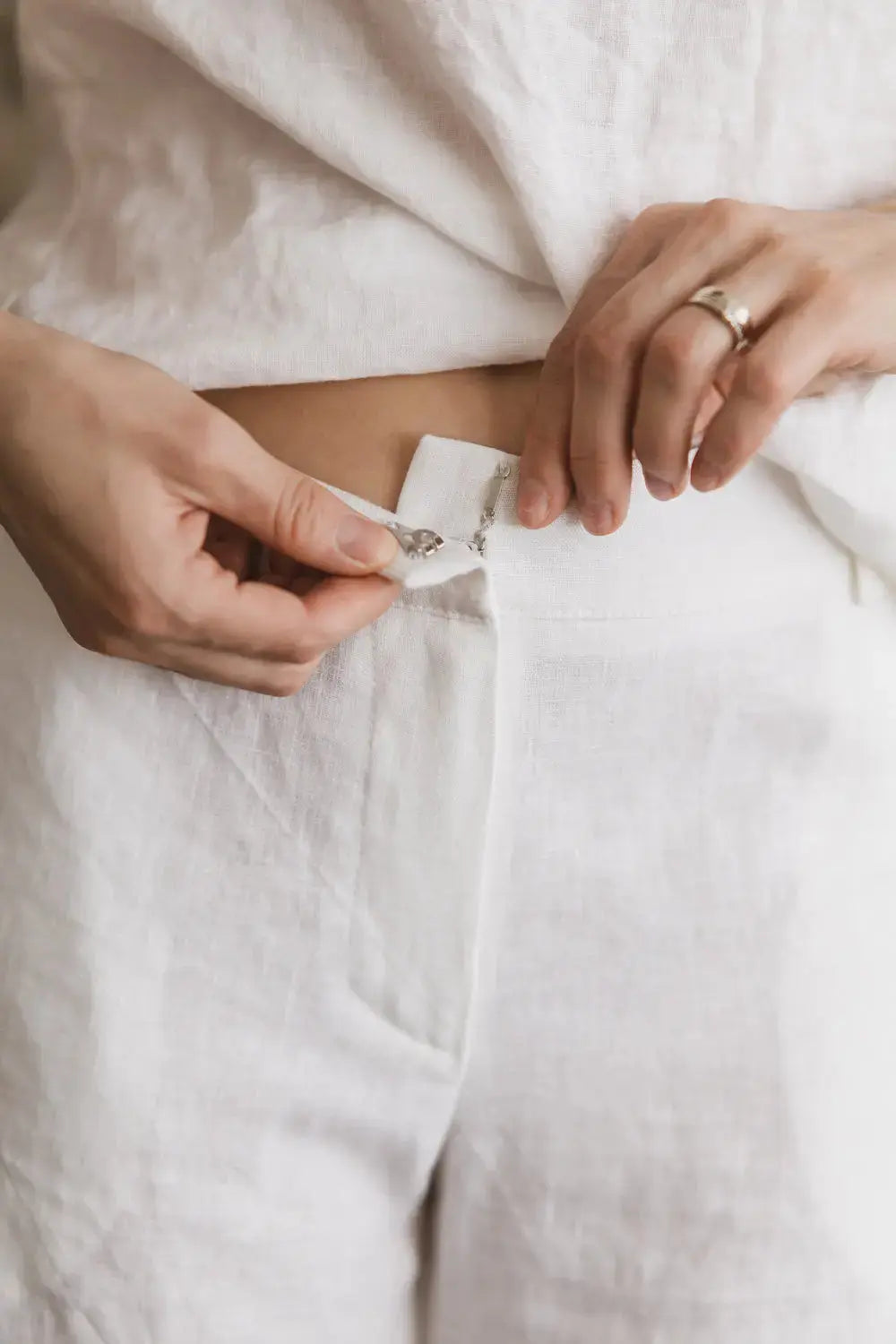 Close-up detail of high-waist closure on premium linen pants with hook closure