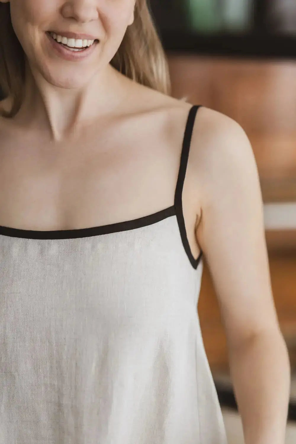Close-up of square neckline and contrast black trim on a natural linen slip dress